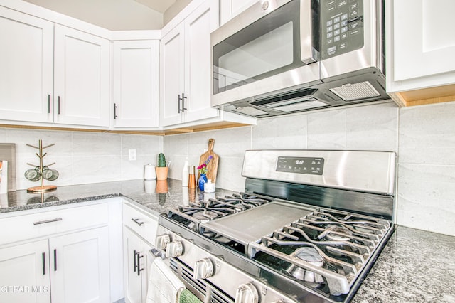 kitchen with stone counters, appliances with stainless steel finishes, white cabinets, and backsplash