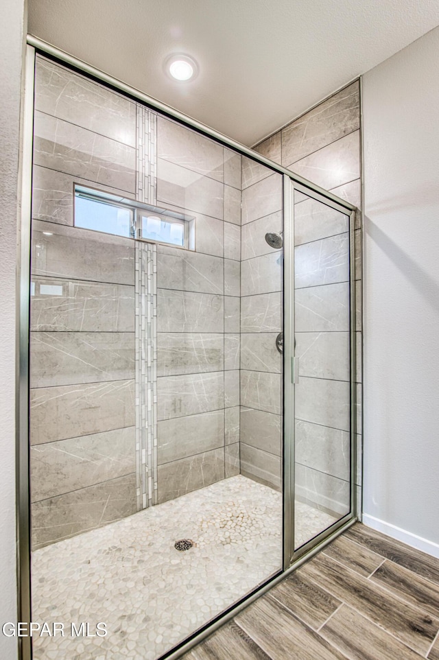bathroom featuring baseboards, a shower stall, and wood finished floors