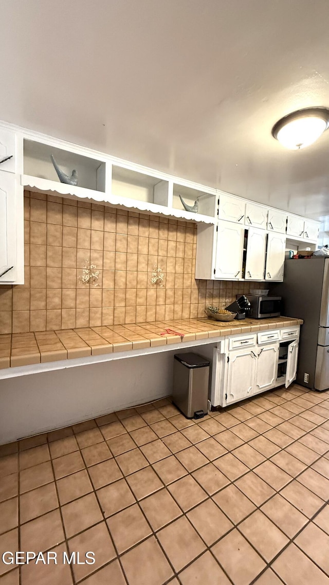 kitchen with stainless steel appliances, open shelves, light tile patterned floors, white cabinetry, and tile countertops