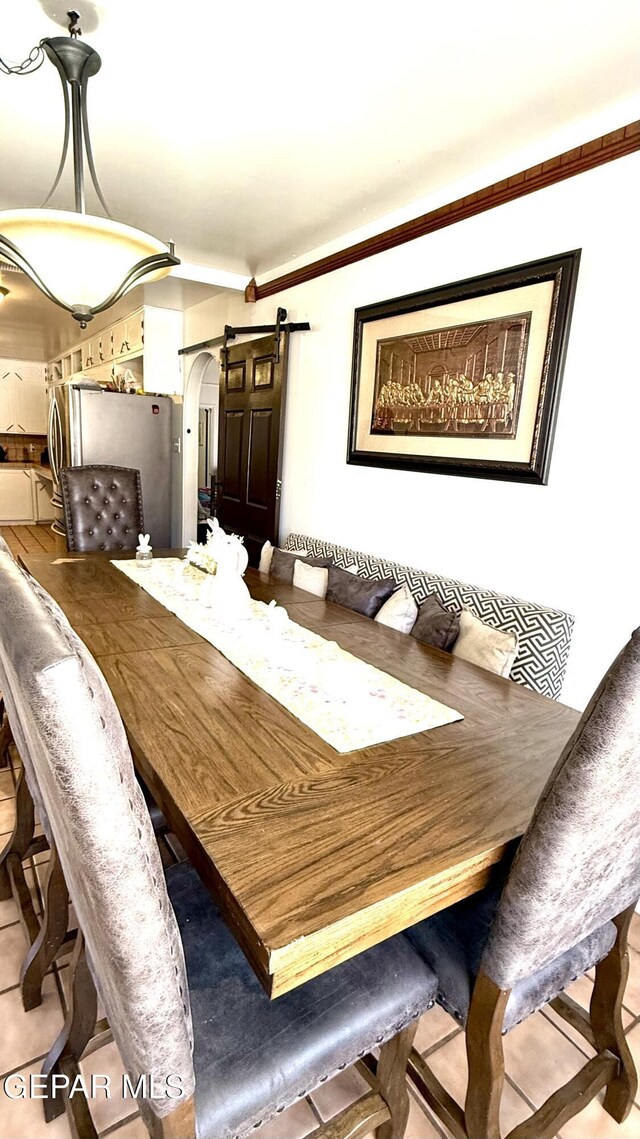 dining area with ornamental molding, arched walkways, and a barn door