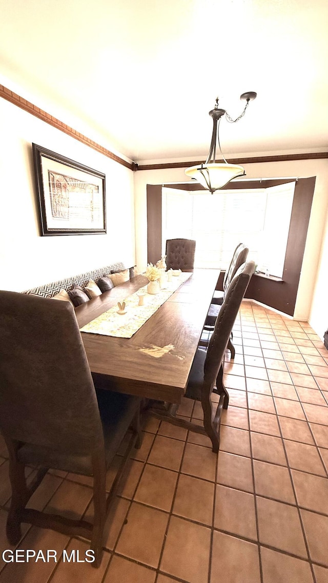 dining space with tile patterned floors and crown molding