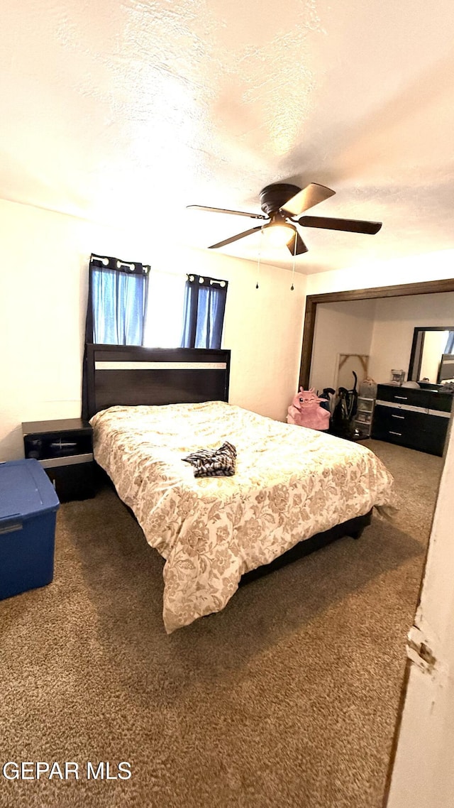 carpeted bedroom featuring ceiling fan and a textured ceiling