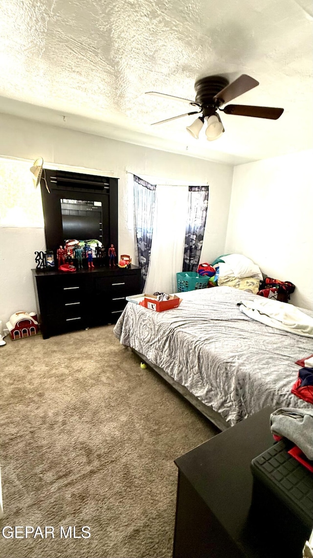 carpeted bedroom featuring a textured ceiling and ceiling fan