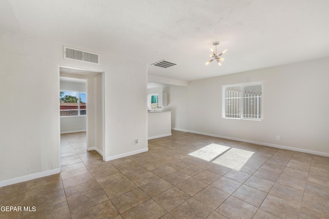 unfurnished room featuring a notable chandelier, visible vents, tile patterned floors, and baseboards