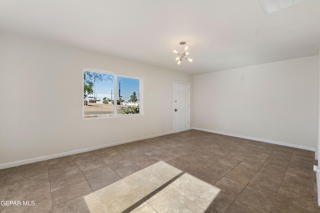 spare room featuring an inviting chandelier and baseboards