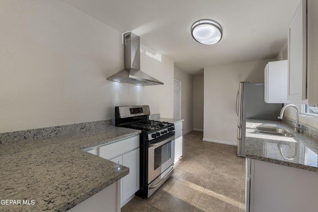 kitchen featuring white cabinets, gas range, wall chimney range hood, and a sink