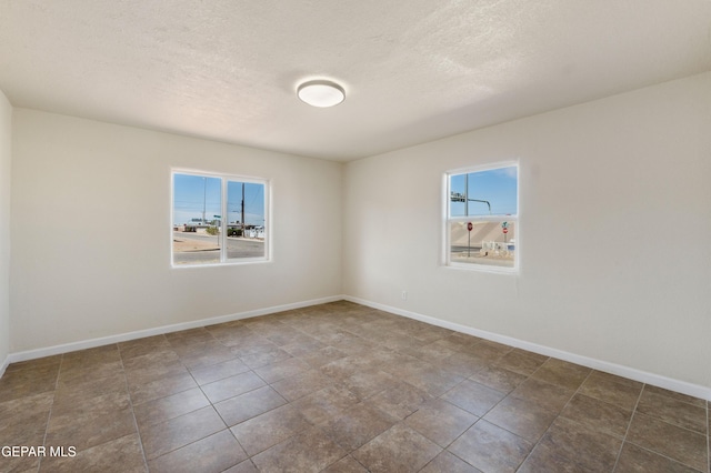 spare room with baseboards and a textured ceiling