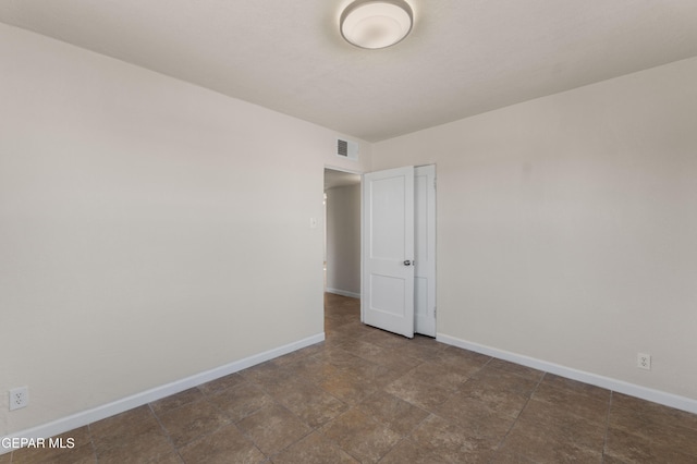 unfurnished room with baseboards and visible vents