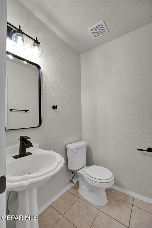 12617 Sun Spirit Dr, El Paso, TX 79938 - half bath with toilet, tile patterned flooring, baseboards, and a textured ceiling