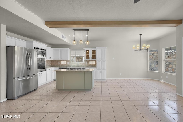 12617 Sun Spirit Dr, El Paso, TX 79938 - kitchen featuring appliances with stainless steel finishes, beamed ceiling, backsplash, a chandelier, and light tile patterned floors