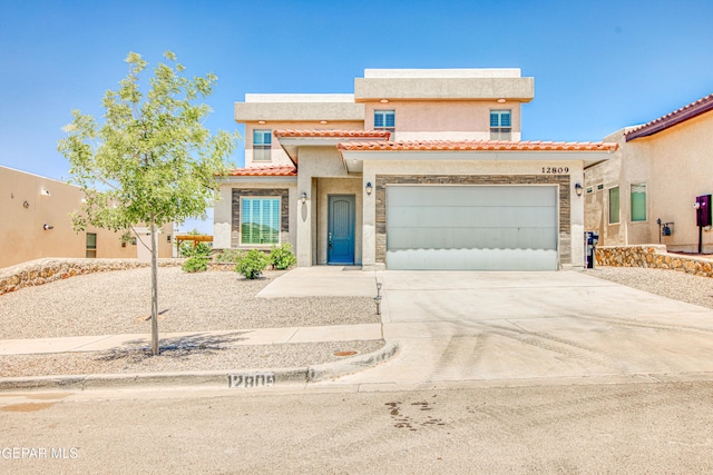 mediterranean / spanish-style home with a garage, a tiled roof, concrete driveway, and stucco siding