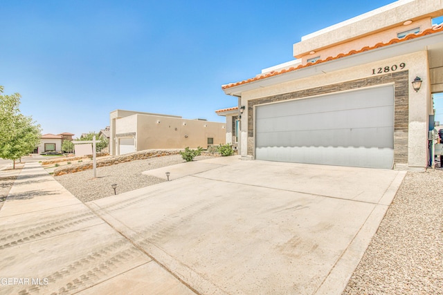 view of side of home with a garage, stucco siding, driveway, and stone siding