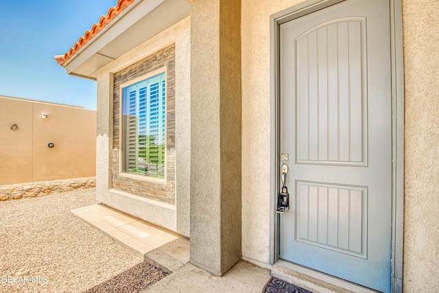 doorway to property featuring stucco siding and a tiled roof
