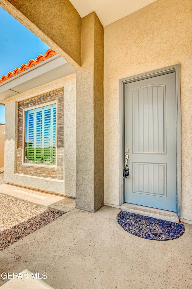 doorway to property featuring stucco siding