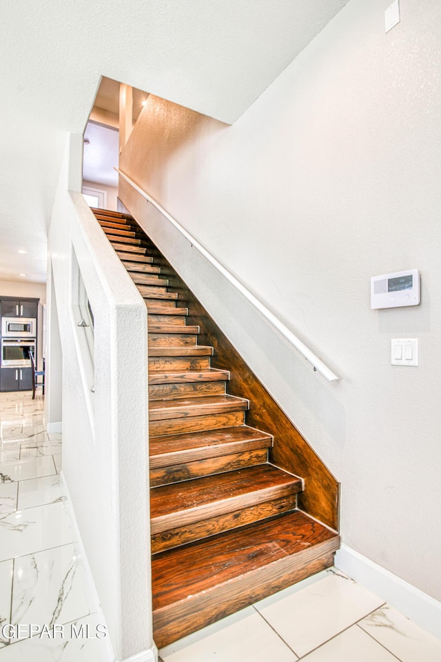 stairs featuring baseboards and marble finish floor