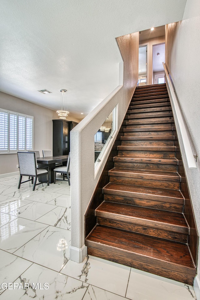 staircase featuring baseboards, a textured ceiling, marble finish floor, and visible vents