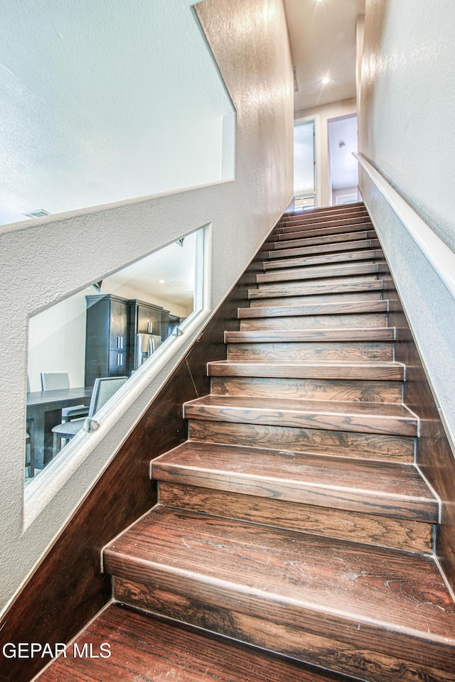 stairway with a textured wall and wood finished floors