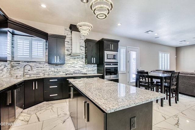 kitchen featuring appliances with stainless steel finishes, a sink, marble finish floor, and a center island