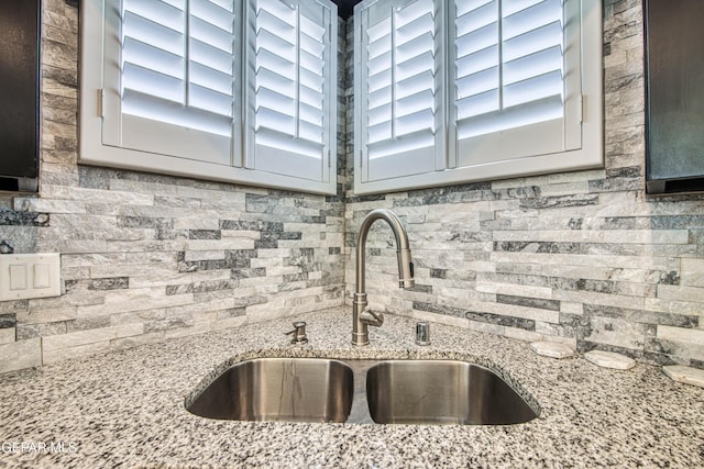 interior details featuring light stone counters, decorative backsplash, and a sink
