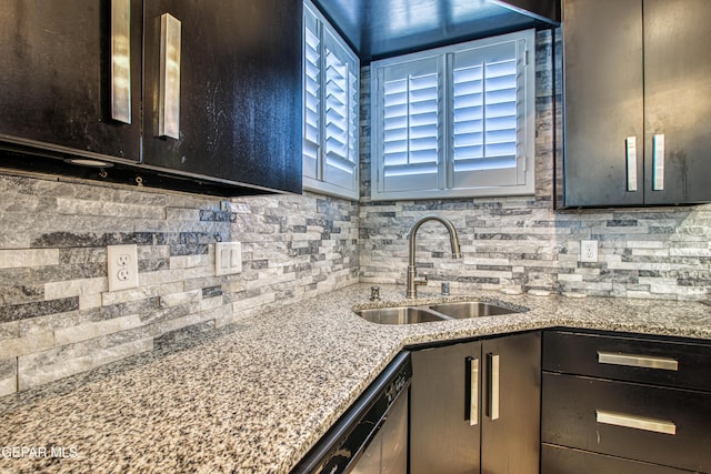 kitchen with dark brown cabinetry, backsplash, dishwasher, a sink, and light stone counters