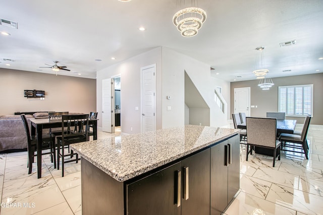 kitchen featuring visible vents, open floor plan, marble finish floor, and ceiling fan with notable chandelier