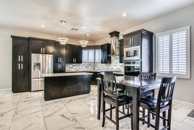 kitchen featuring stainless steel appliances, baseboards, decorative backsplash, a kitchen island, and visible vents