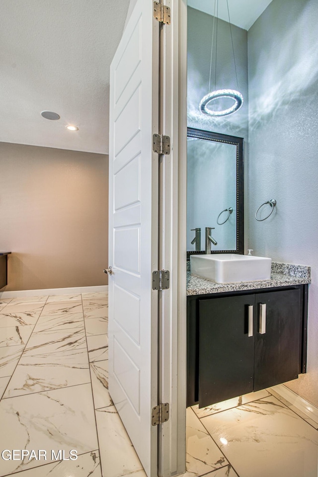 bathroom with baseboards, marble finish floor, and vanity