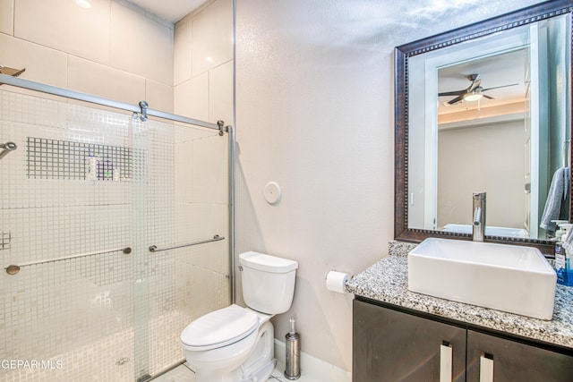 bathroom featuring ceiling fan, vanity, toilet, baseboards, and a stall shower