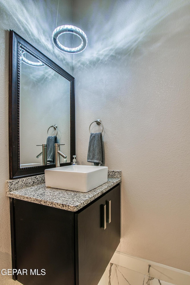 bathroom featuring baseboards, vanity, and marble finish floor