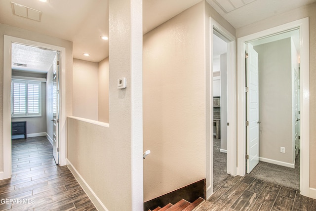 corridor featuring visible vents, baseboards, and wood finish floors