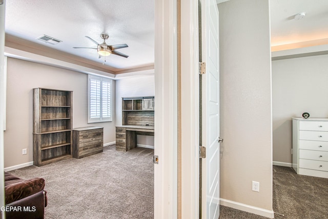 unfurnished office featuring baseboards, a ceiling fan, carpet flooring, and visible vents