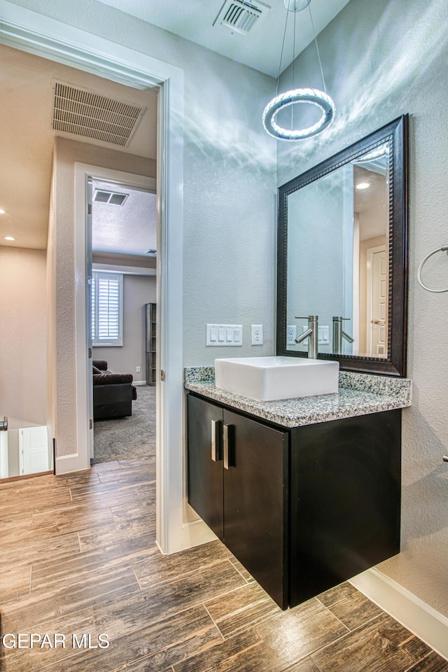 bathroom featuring a textured wall, visible vents, wood finished floors, and vanity