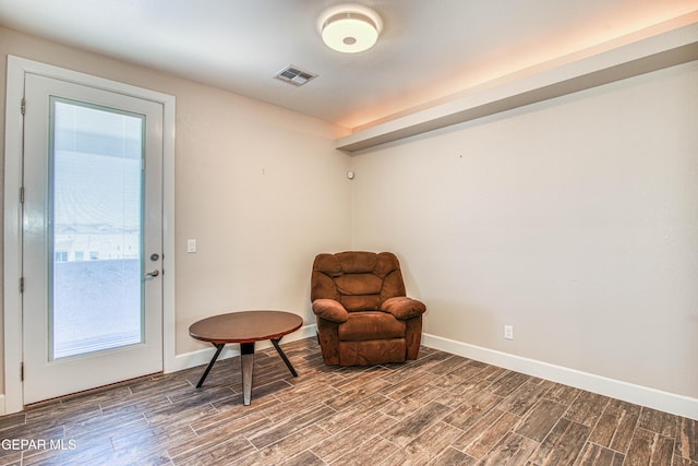 sitting room with baseboards, plenty of natural light, wood finish floors, and visible vents