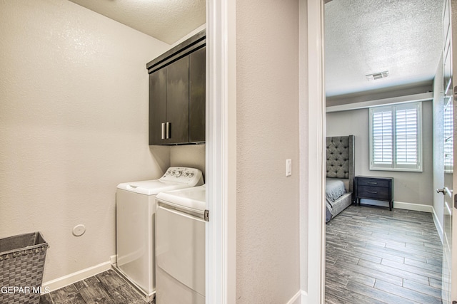 laundry room with visible vents, wood finished floors, a textured ceiling, cabinet space, and independent washer and dryer