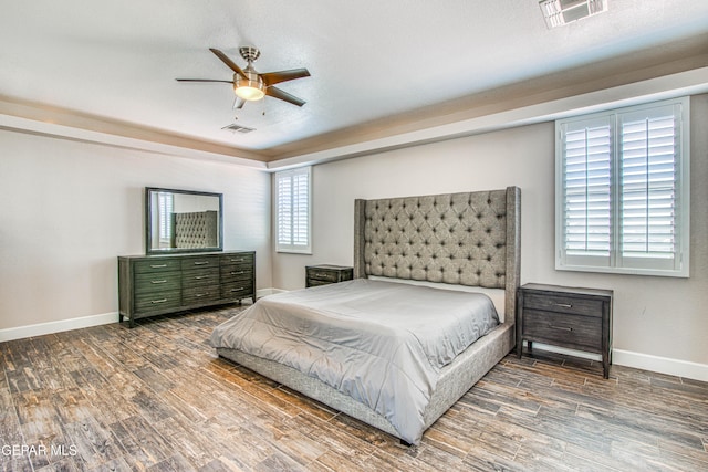 bedroom featuring baseboards, a ceiling fan, wood finished floors, and visible vents