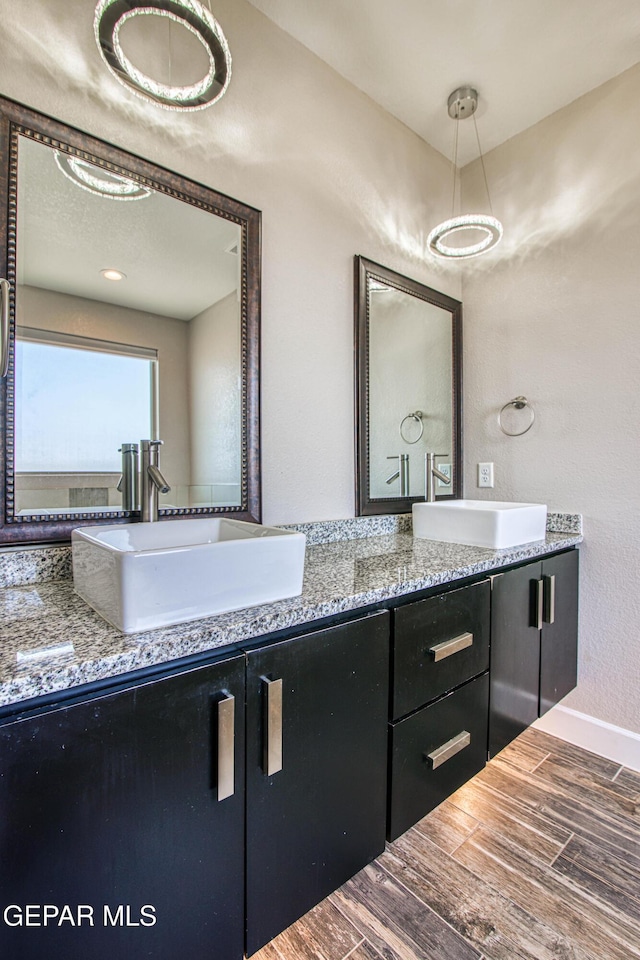 bathroom featuring double vanity, baseboards, a sink, and wood finished floors