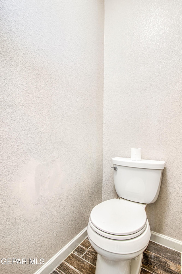 bathroom with baseboards, wood finished floors, and toilet