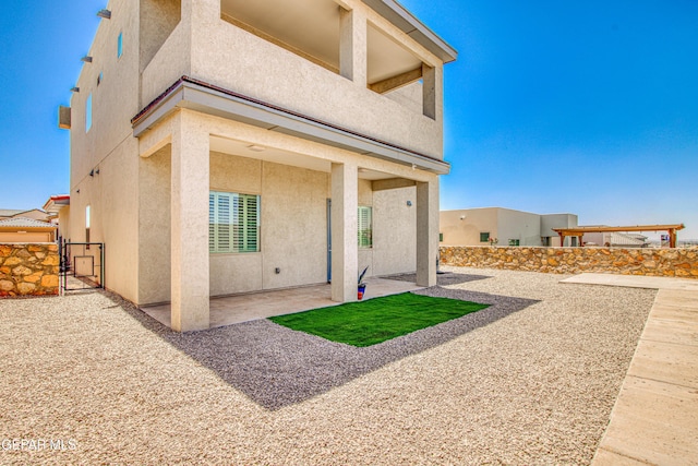 back of property with a patio, fence, a gate, and stucco siding