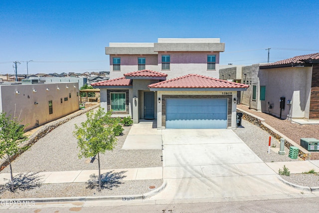 mediterranean / spanish-style home with concrete driveway, a tiled roof, an attached garage, and stucco siding