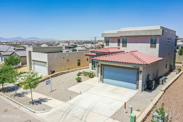 view of front of house with a tiled roof, driveway, a garage, a mountain view, and stucco siding