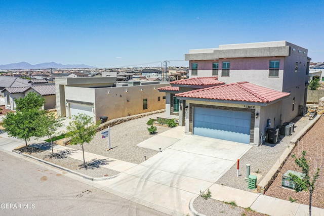 view of front of property featuring central AC, a tile roof, a garage, stucco siding, and driveway