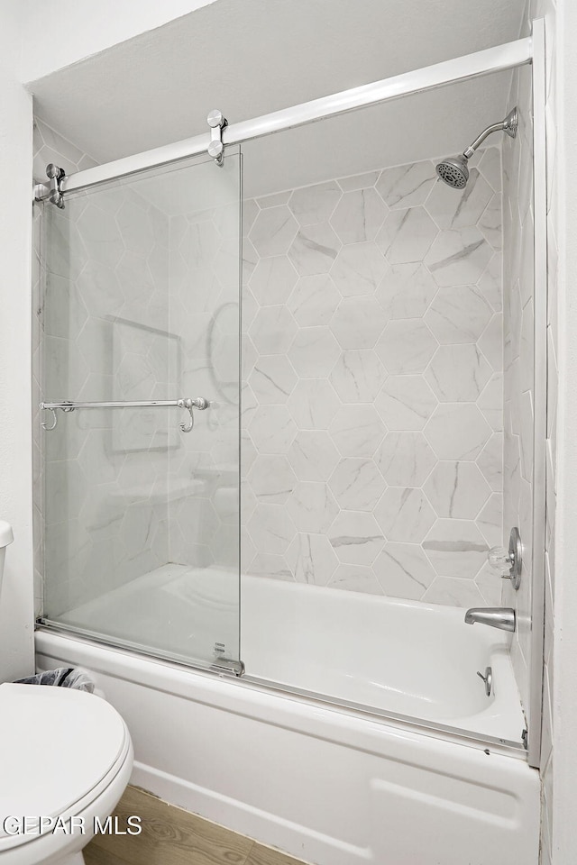 bathroom featuring bath / shower combo with glass door and toilet