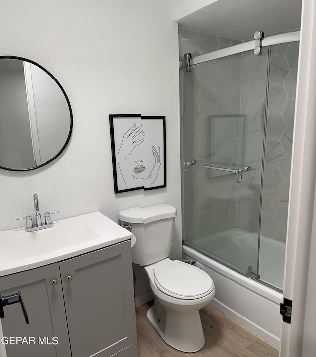 full bathroom with vanity, bath / shower combo with glass door, toilet, and wood finished floors