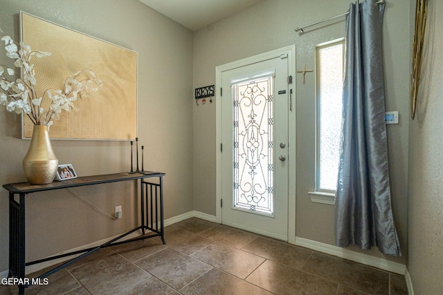 foyer featuring baseboards, tile patterned floors, and a wealth of natural light