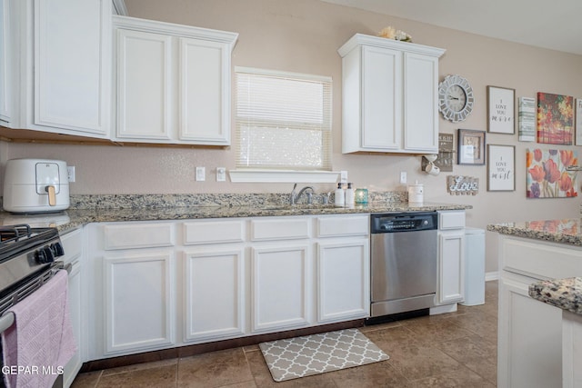 kitchen with light stone counters, a sink, white cabinets, and stainless steel appliances