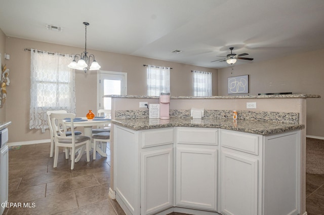 kitchen with a healthy amount of sunlight, baseboards, ceiling fan with notable chandelier, and visible vents