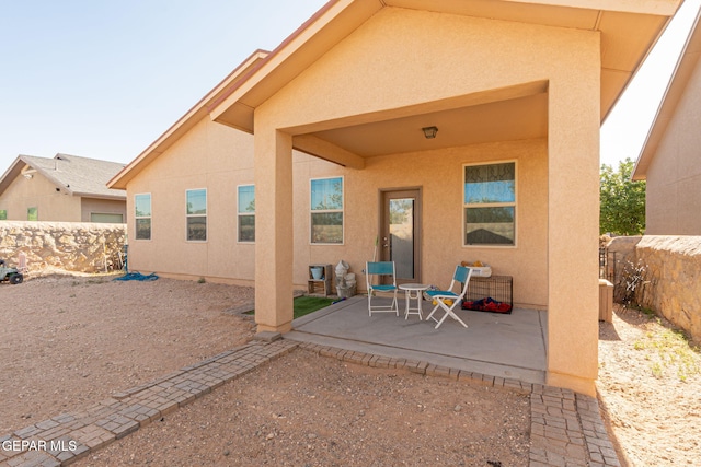 rear view of property with fence, a patio area, and stucco siding