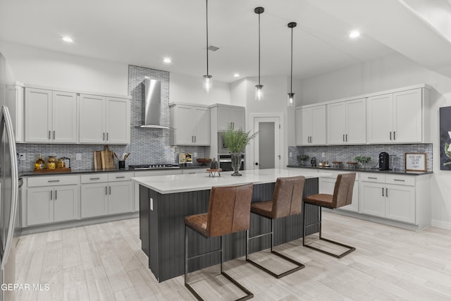 837 Durham Way, Horizon City, TX 79928 - kitchen featuring wall chimney exhaust hood, backsplash, a breakfast bar area, a kitchen island, and black stovetop