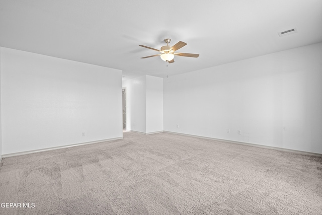 carpeted spare room featuring visible vents, a ceiling fan, and baseboards