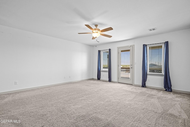 spare room featuring carpet flooring, a ceiling fan, baseboards, and visible vents